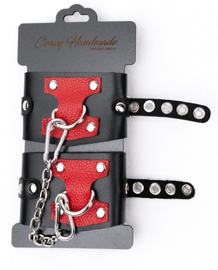 Кожаные наручники с контрастным декором и заклепками имеют кольца для крепления и металлическую сцепку.