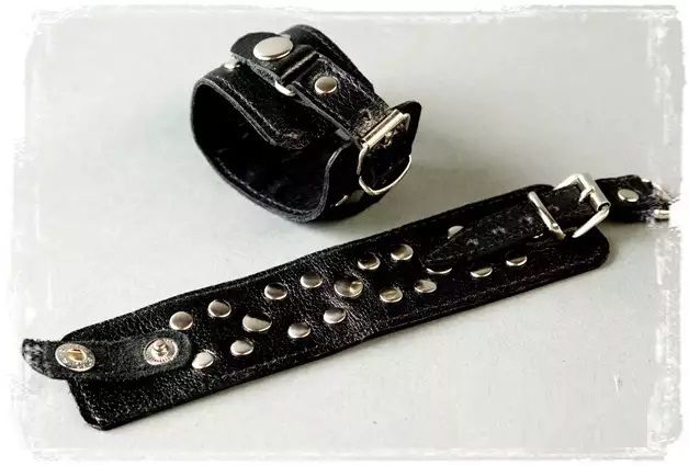 Наручники узкие, декорированные заклепками. Размер наручников регулируется застежкой пряжкой. Можно носить как декоративные браслеты. Выполнены из натуральной кожи черного цвета.