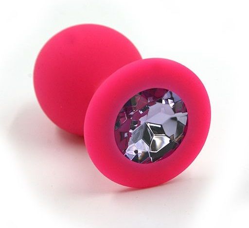 Анальная пробка из силикона розового цвета, размер M. Страз в основании круглой формы,  выполнен из стекла светло-фиолетового цвета. Упакована в вельветовый мешочек для хранения. Вес - 46,5 граммов.