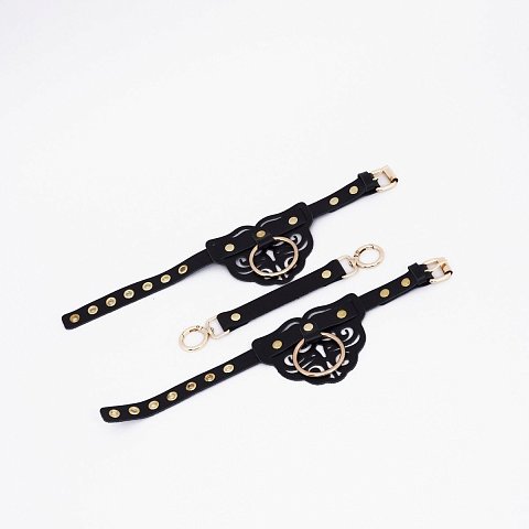 Оковы с декоративными резными узорами изготовлены из натуральной кожи. Декорированы золотой фурнитурой и клепками. В комплект также входит соединительный кожаный элемент с двумя карабинами, с помощью которого можно зафиксировать между собой ноги. Доставляется в фирменной упаковке в виде брендированной деревянной подложки.