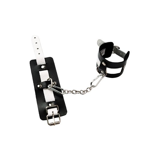 Оковы состоят из двух деталей: основа прямоугольной формы из натуральной кожи черного цвета и ремешок белого цвета с прочной хромированной фурнитурой в виде овального кольца. Расположение ремешка через прорези основной части является декоративным решением, а также служит для лучшей регулировки размера. В комплект входит соединительная цепочка с двумя карабинами.  Общая длина - 32 см.<br> Длина манжеты - 15,5 см.<br> Ширина манжеты - 6 см.<br> Обхват - 20-29 см.